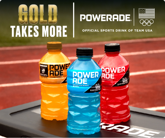 GOLD Takes More. Three bottles of powerade sit atop a cooler aside an Olympic running track